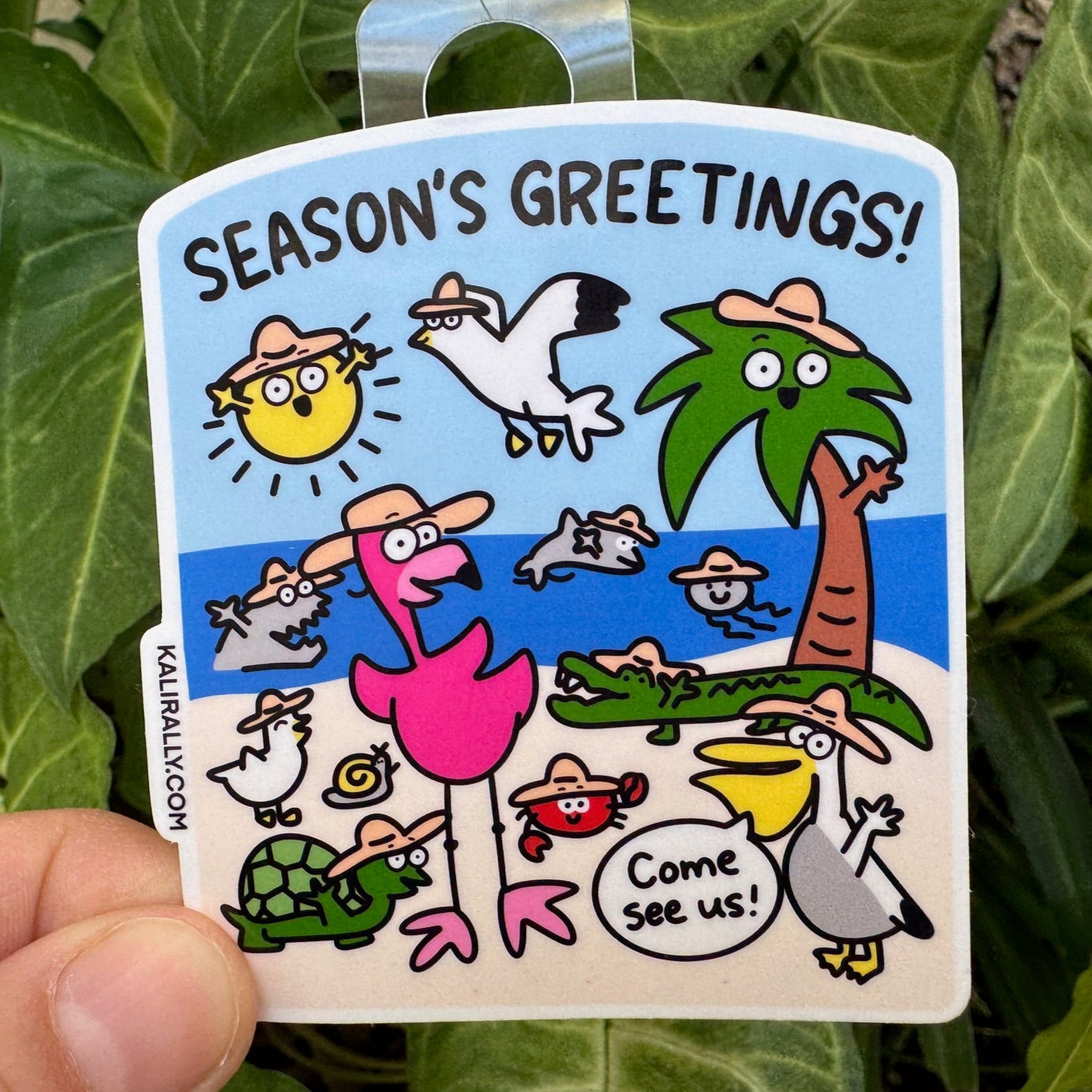 Vinyl beach sticker with the phrase “Seasons Greetings!” and beach-themed graphics — perfect holiday decal, by Kalirally