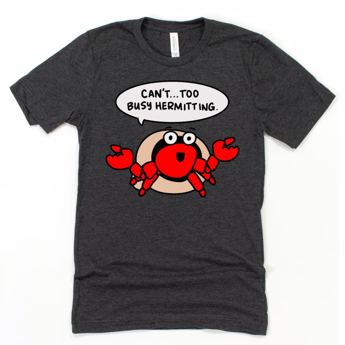 Flat lay of Kalirally’s Heather Dark Grey t-shirt with “Can't. Too Busy Hermitting.” cartoon hermit crab tshirt, perfect for introverts.
