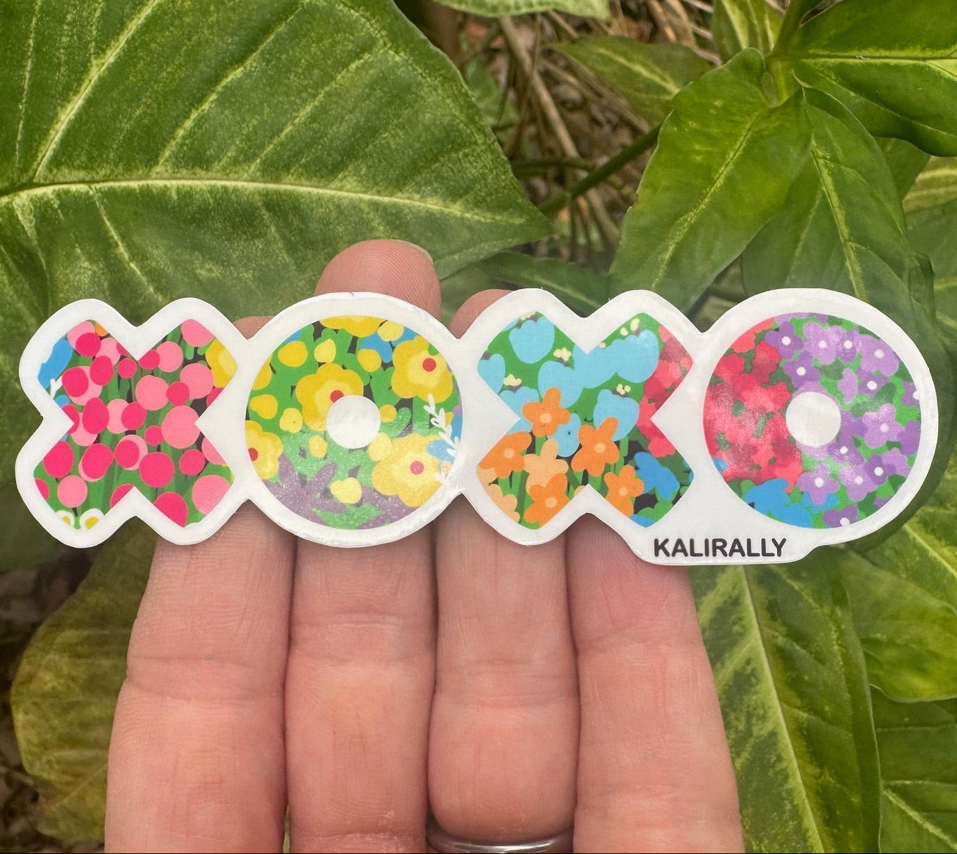 Picture of a 4" long vinyl sticker that says XOXO in vibrant colorful floral letters.