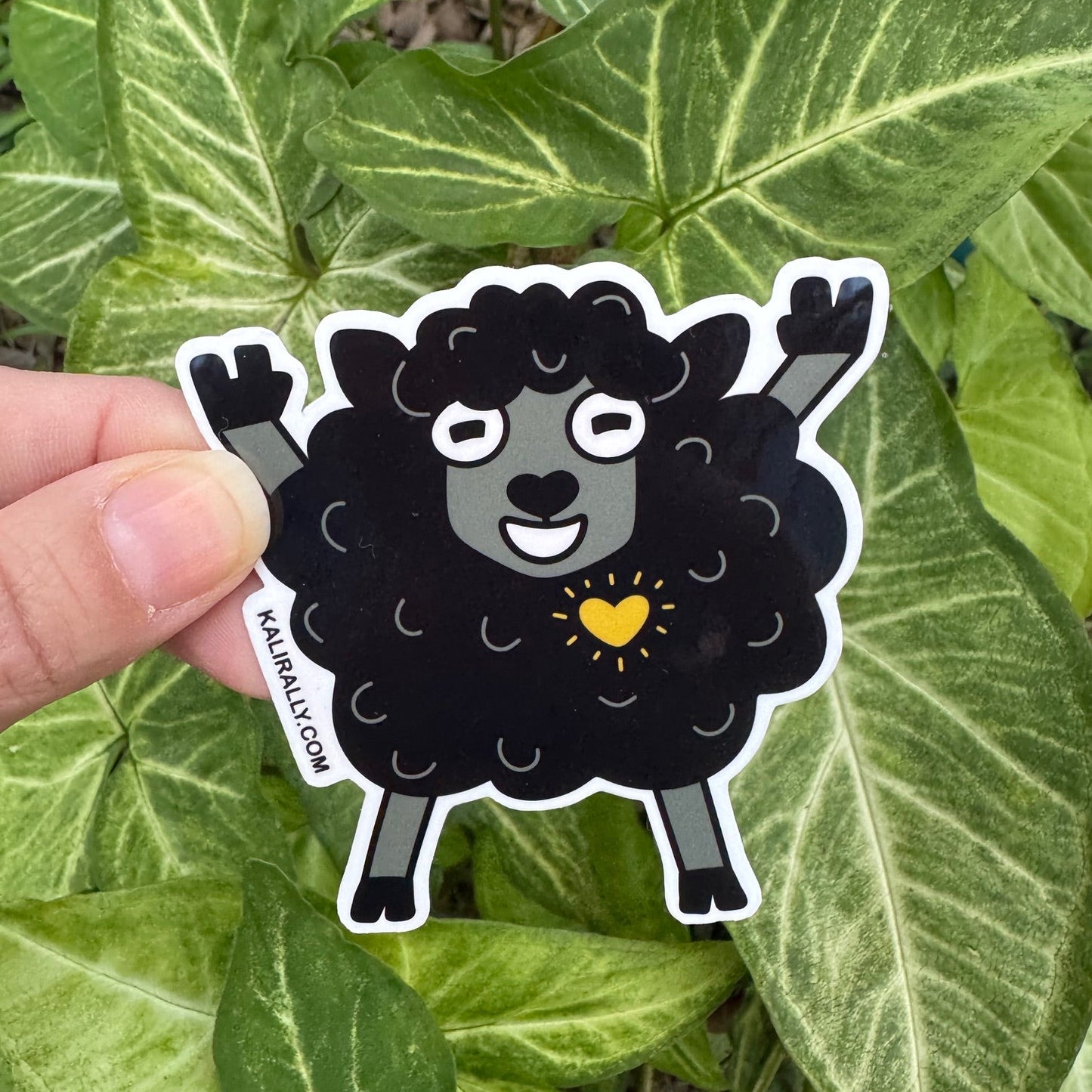 Cartoon black sheep sticker doing rock and roll stance, funny water resistant decal for music lovers and playful rebels Kalirally