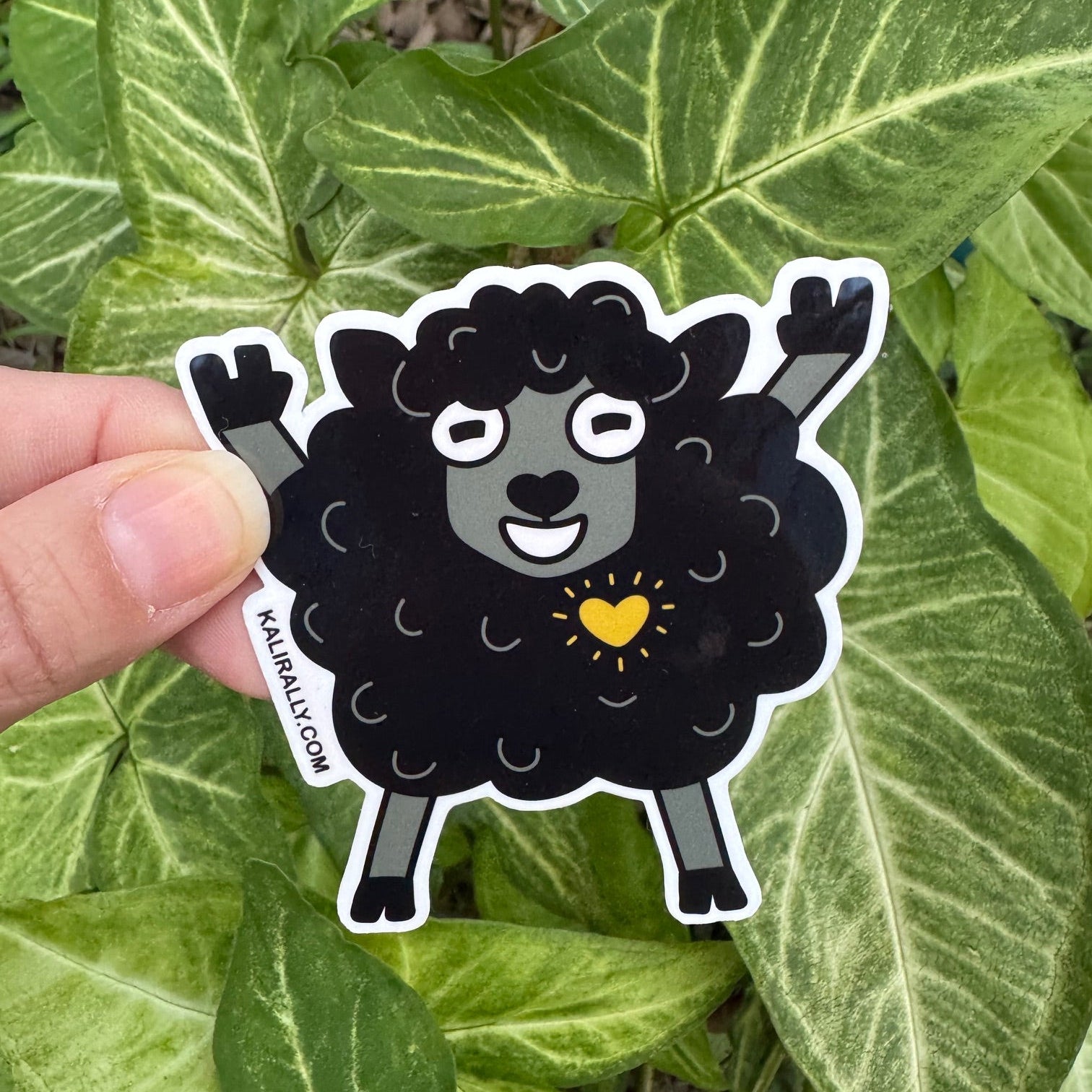 Cartoon black sheep sticker doing rock and roll stance, funny water resistant decal for music lovers and playful rebels Kalirally
