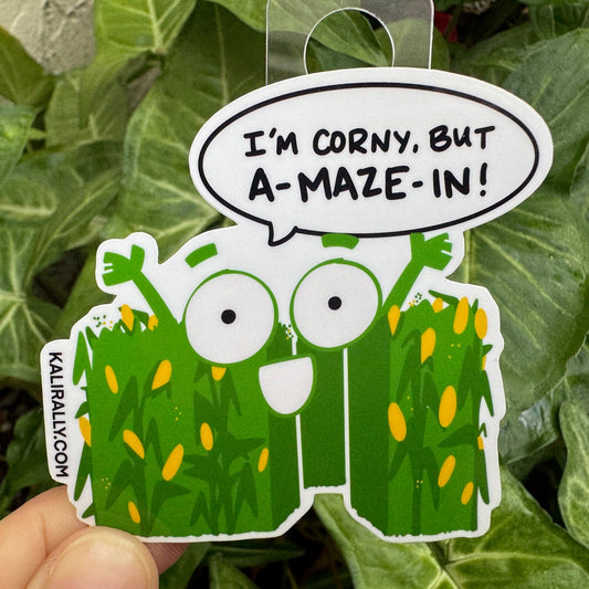 Cartoon corn sticker with the phrase “I’m corny but A-MAZE-IN!” funny punny corn maze decal, by Kalirally.