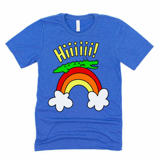 Flat lay mock up of a Heather True Royal Blue alligator shirt with cartoon gator waving “Hiiii” from a rainbow