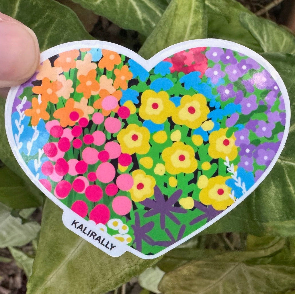 Photo of a vinyl sticker in the shape of a heart, filled with a colorful and bright floral pattern, by Kalirally.