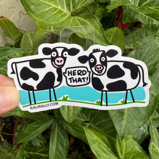 Cartoon cow sticker with phrase “Herd That!” funny animal decal by Kalirally