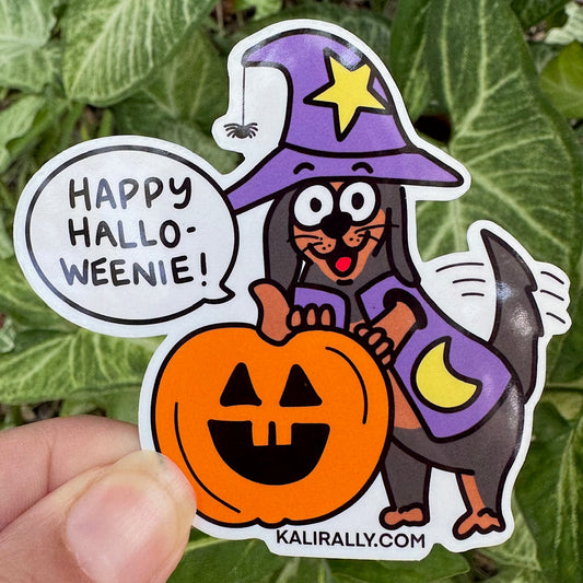Halloween Weiner Dog Sticker with cartoon dachshund in costume and phrase “Happy Halloweenie!”, cute Halloween decal by Kalirally