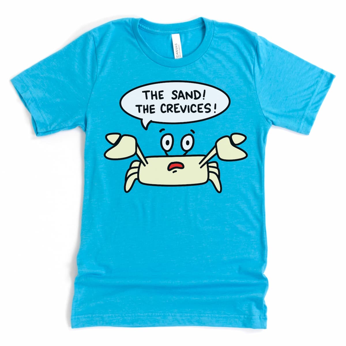 Kalirally’s beach shirt in heather aqua, laid flat to show off a Sand Crab and the phrase “The Sand! The Crevices!”

