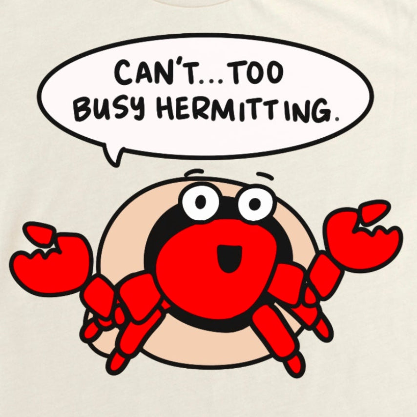Beige t-shirt with a cartoon hermit crab and humorous text that says, "Can't... too busy hermitting" by Kalirally