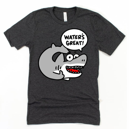 Flat lay of Kalirally shark t shirt in heather dark grey featuring a cartoon shark saying “Water’s great!” with playful beach vibes.