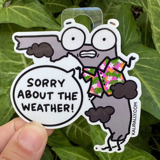Funny Florida souvenir sticker with rainy weather joke, "Sorry about the weather!" from a Cartoon Florida that's grey but wearing a tropical shirt.