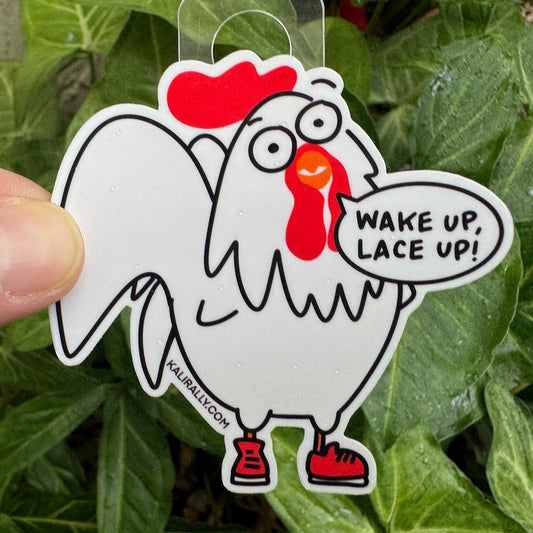 Photo of a vinyl glossy sticker of a cartoon rooster wearing gym shoes with “Wake up, work out” text. A gym sticker, great for water bottles and fitness gear, by Kalirally.