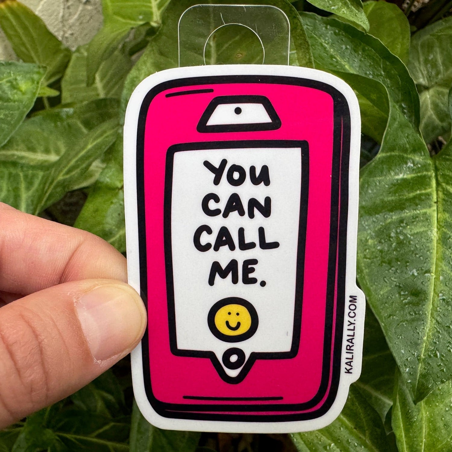 This vinyl water proof sticker has a hot pink cellphone that reads, "You can call me" on the screen, with a little yellow smiley face.